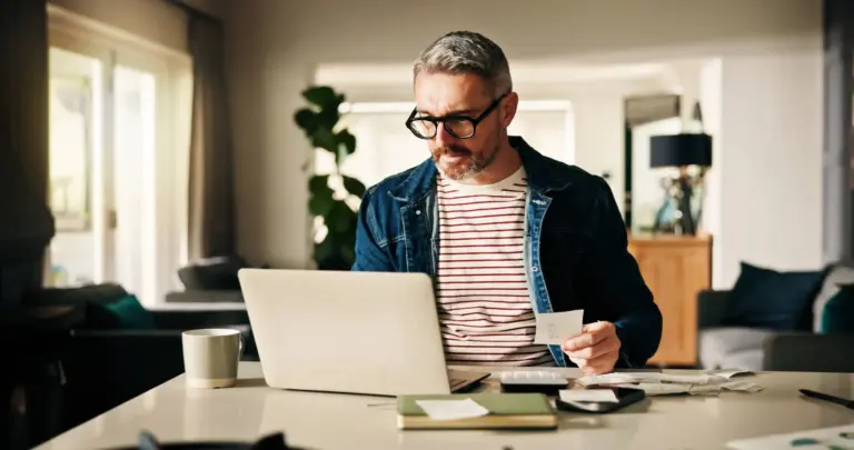 Man sitter vid datorn och räknar personlig budget. Kalp - Kvar att leva på kalkylering